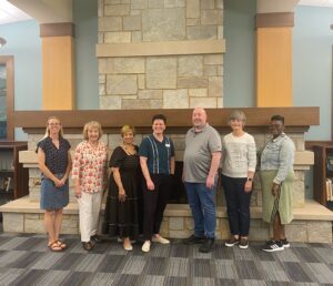 Library board members standing in front of fireplace. 